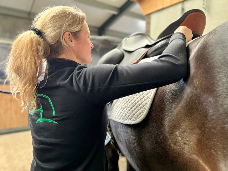 Carole Colling ajustant personnellement une selle, ajusteuse de selles certifiée et ostéopathe équin